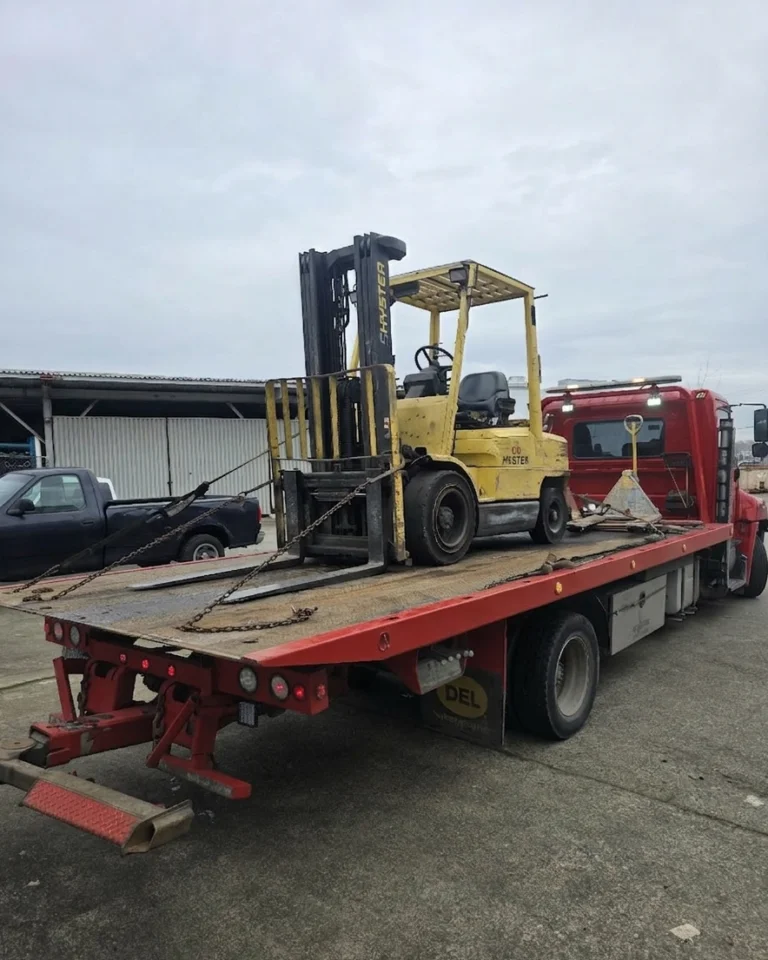 Red flat deck tow truck used for forklift removal across the Lower Mainland